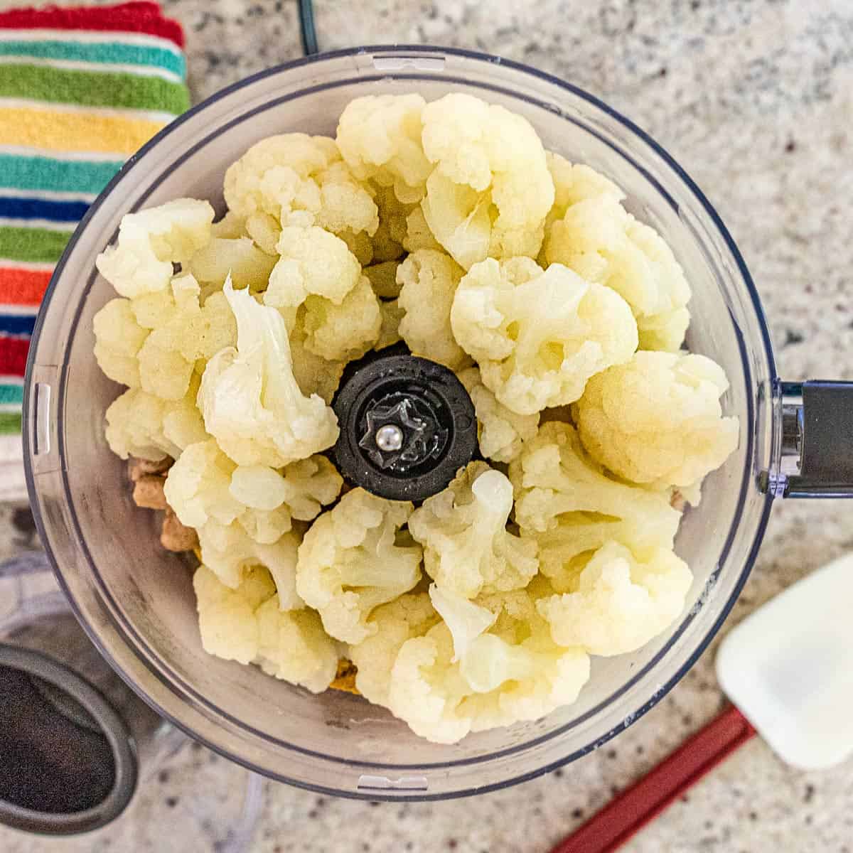 Cooked cauliflower in a food processor to be pureed.