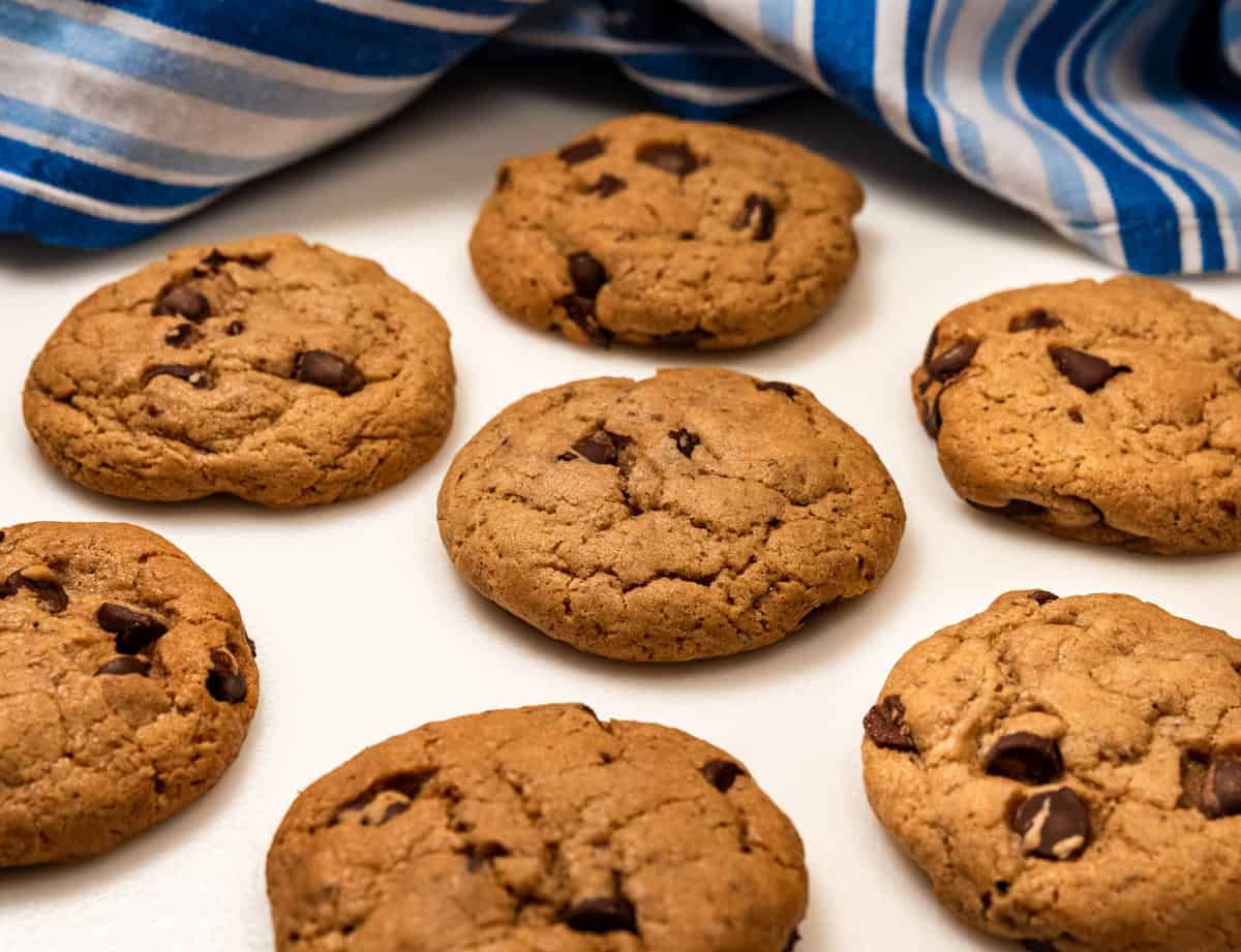 Chocolate chip cookies on a white surface with a blue and white striped towel in the background.