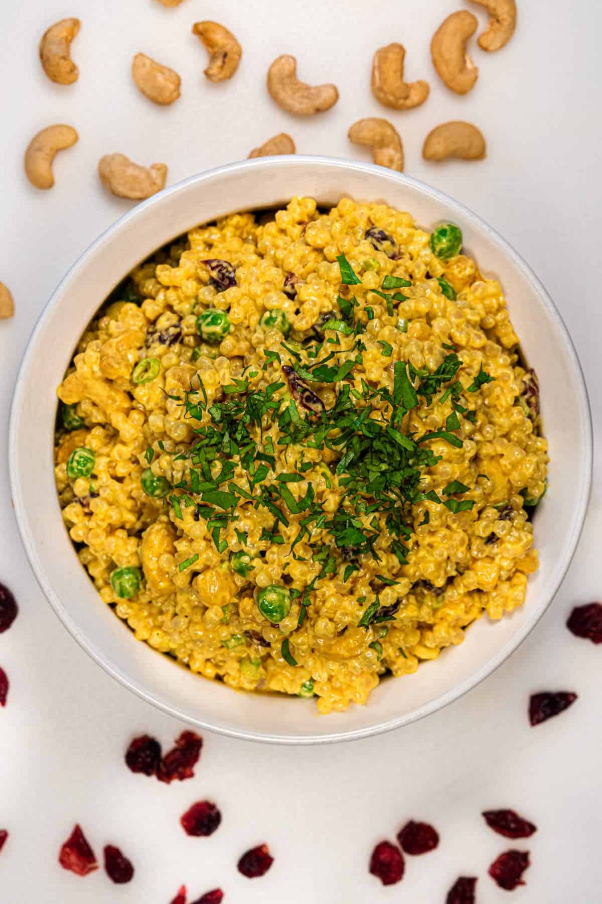 Dish of vegan curried Israeli couscous salad with cashews and cranberries.