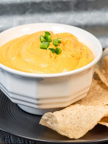 Vegan nacho cheese in a dish with a side of tortilla chips.