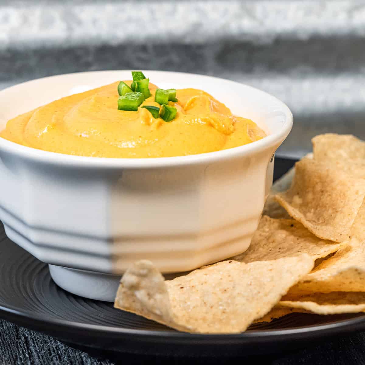 Vegan nacho cheese in a dish with a side of tortilla chips.