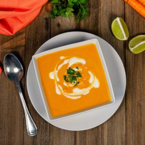 Bowl of vegan carrot ginger soup topped with vegan yogurt.
