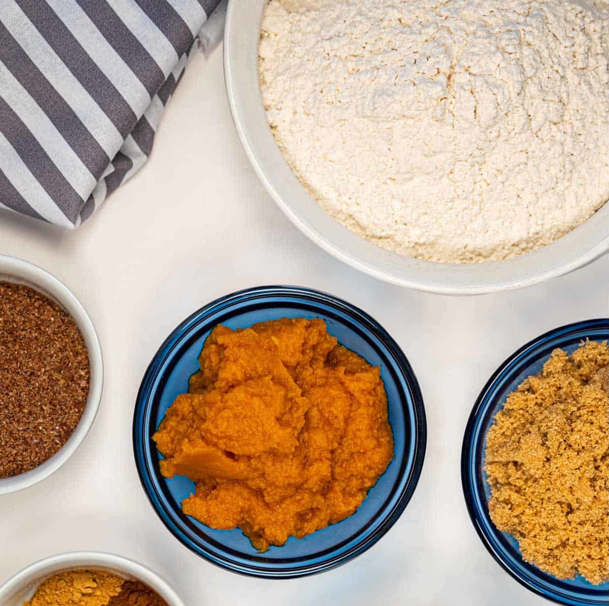 A variety of small dishes filled with pumpkin puree, brown sugar, spices, and flour.