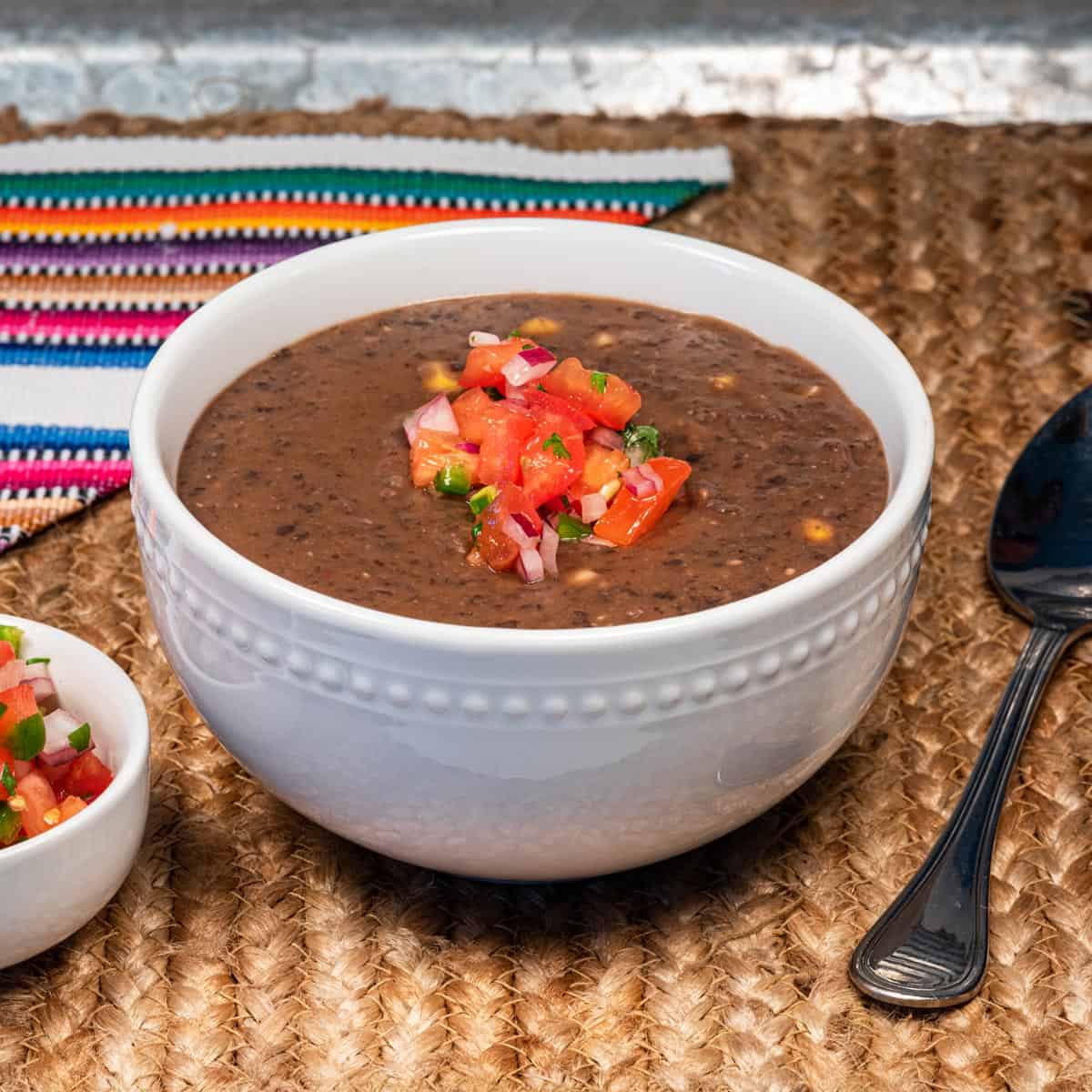 A bowl of vegan chipotle black bean soup topped with pico de gallo.