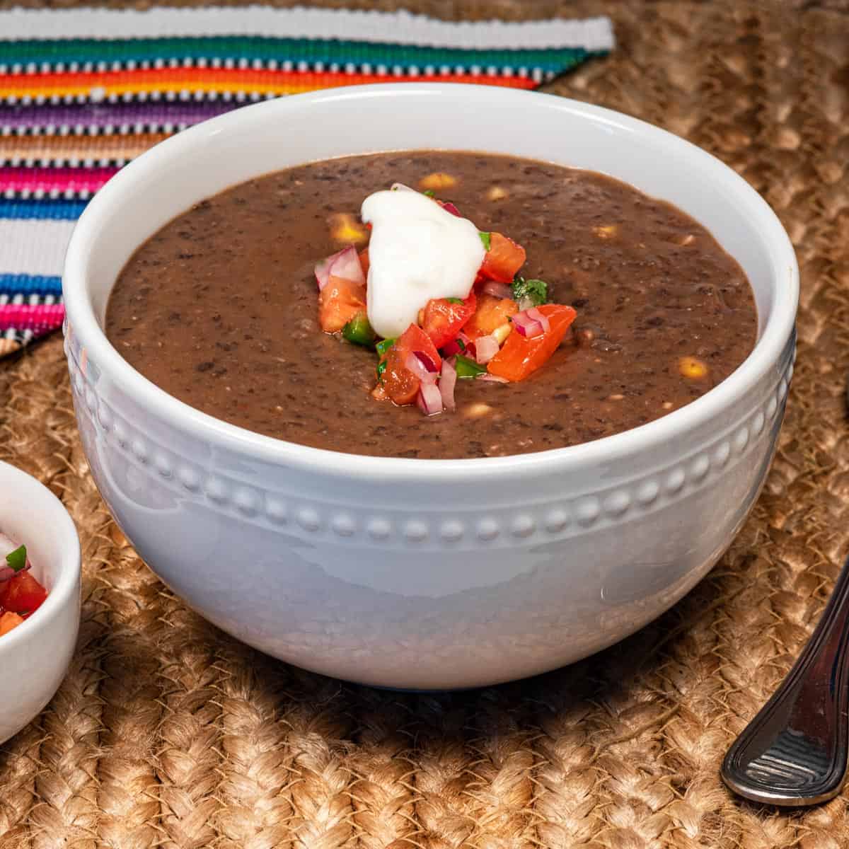 A bowl of vegan chipotle black bean soup topped with vegan sour cream.