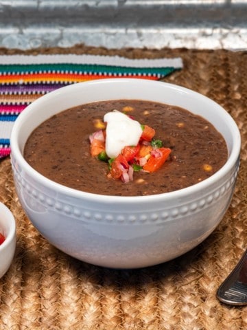 A bowl of vegan chipotle black bean soup topped with vegan sour cream.
