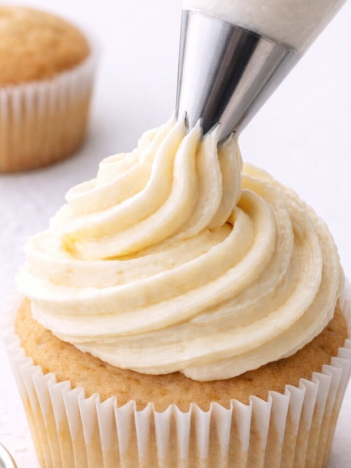 cupcake being piped with dairy free cream cheese frosting