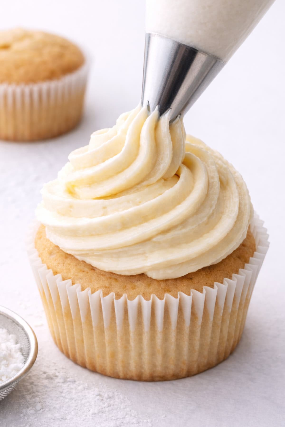 cupcake being piped with dairy free cream cheese frosting