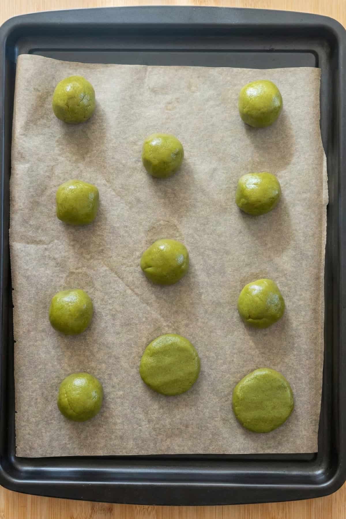 vegan matcha cookie dough balls on a sheet pan.