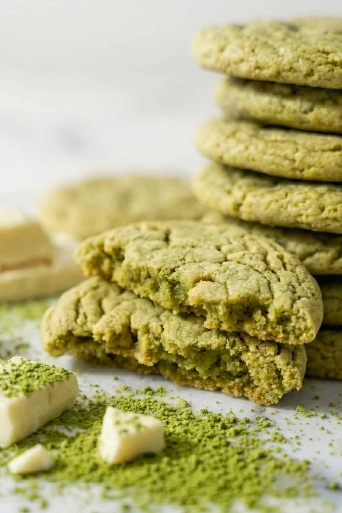 Green matcha cookies with matcha powder and white chocolate chunks on a counter.