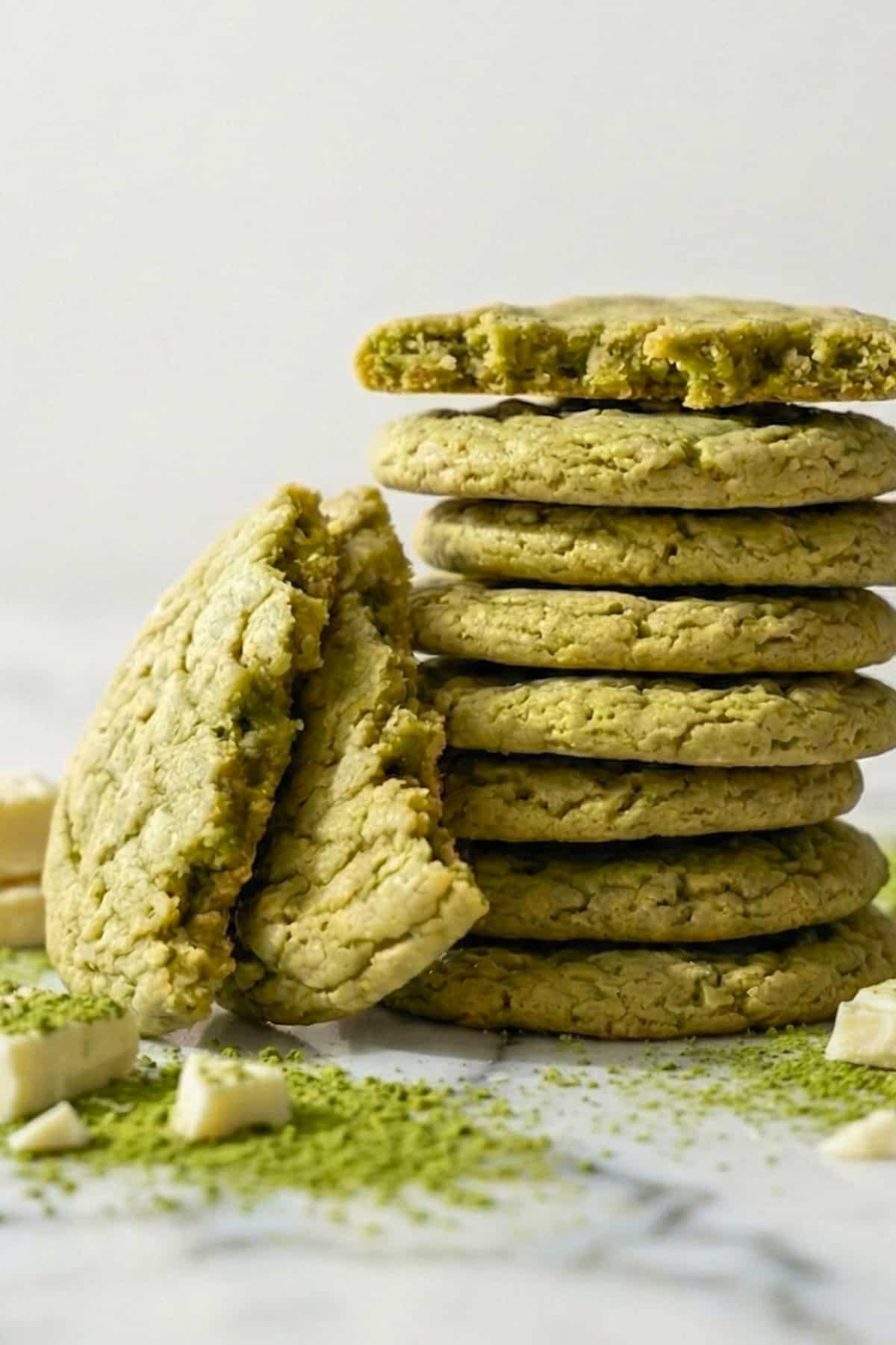 Green matcha cookies with matcha powder and white chocolate chunks on a counter.