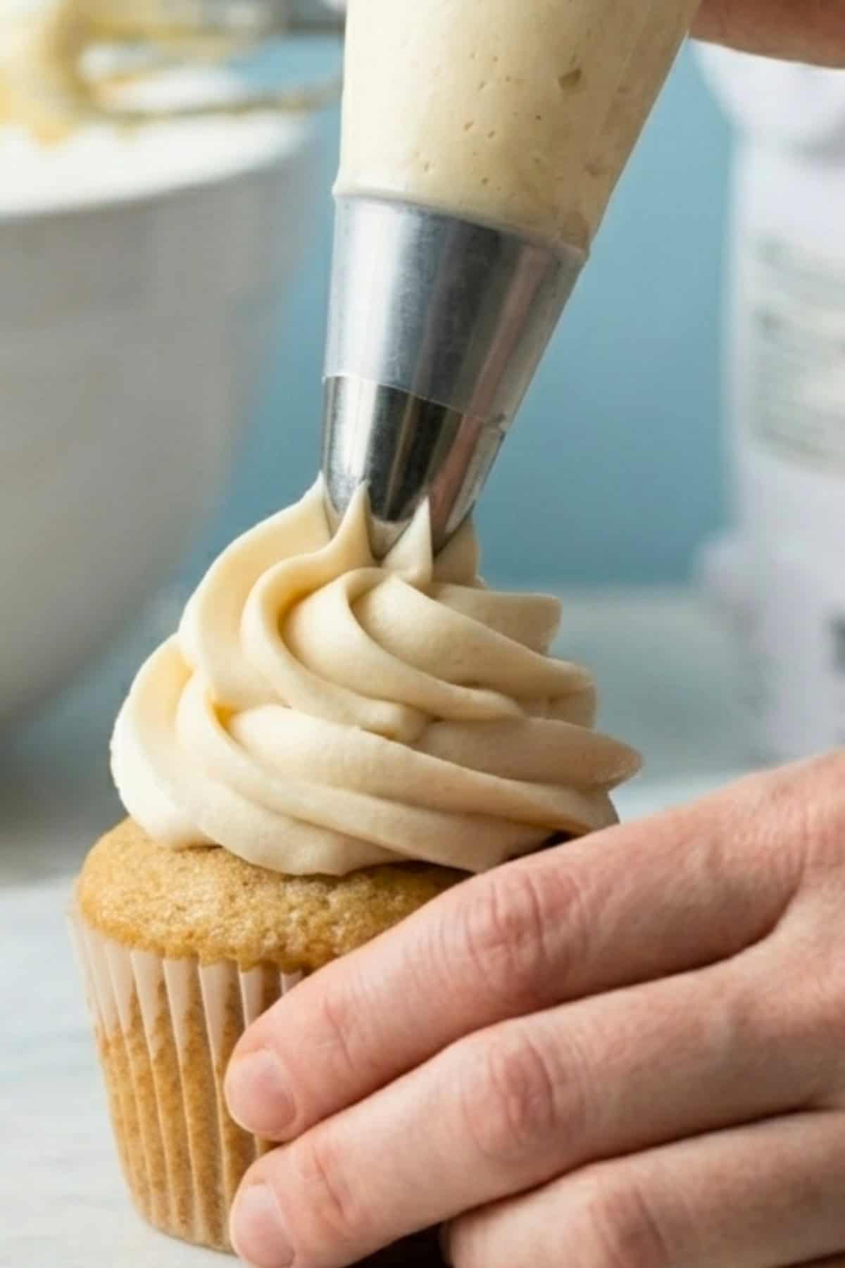 Vegan vanilla buttercream being piped onto a vanilla cupcake.