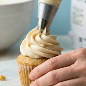 Vegan vanilla buttercream being piped onto a vanilla cupcake.
