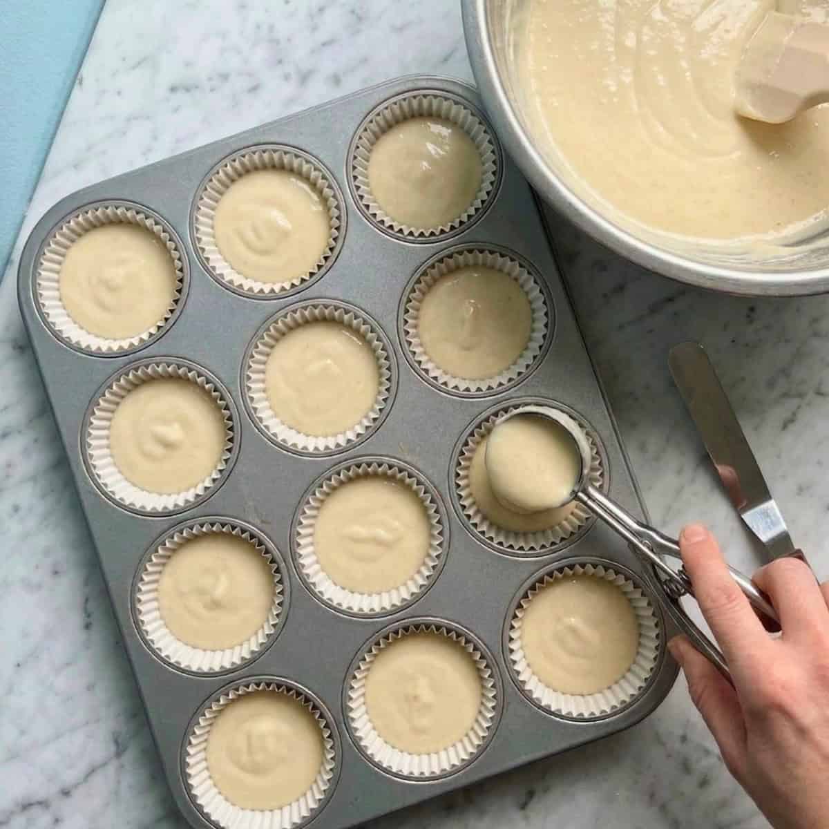 Vegan vanilla cupcake batter being put into a cupcake tin.