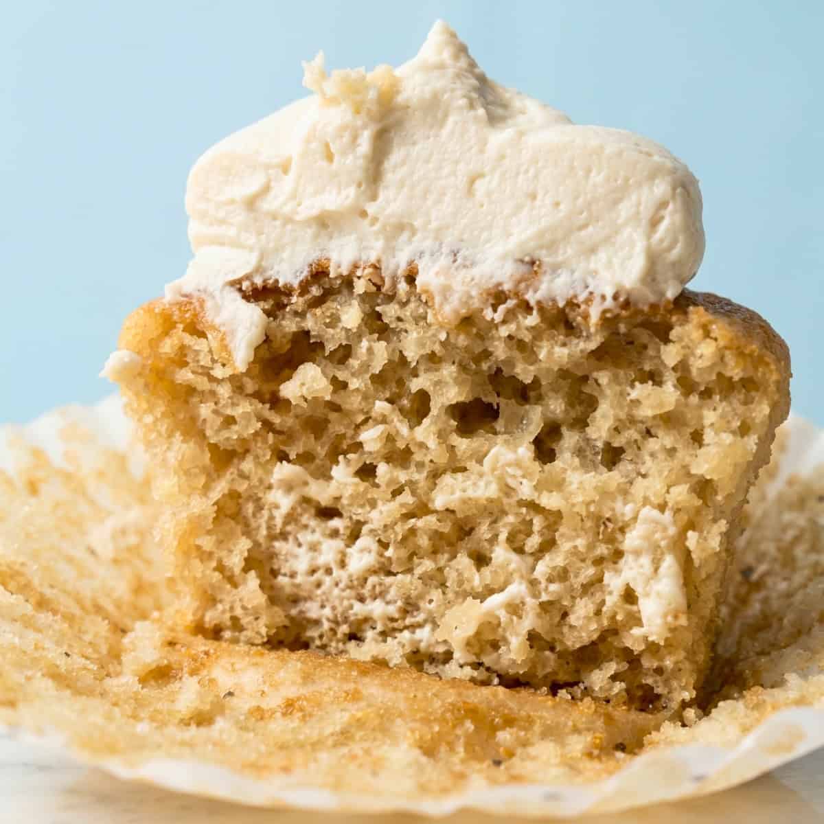 A vegan vanilla cupcake topped with a swirl of white vanilla buttercream frosting.