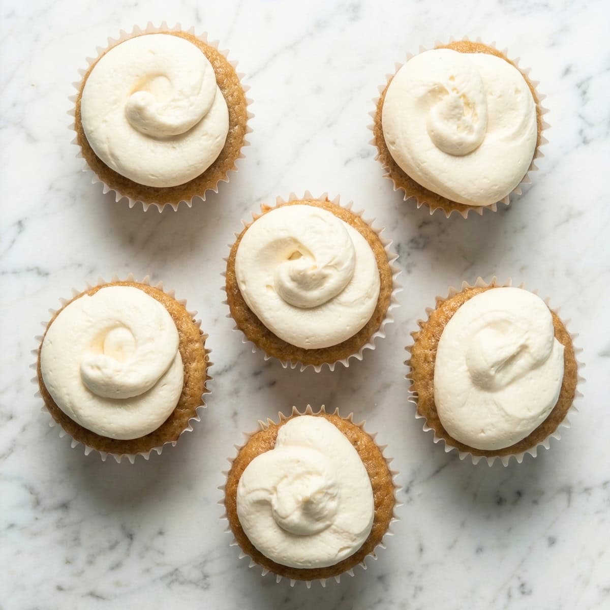 Vegan vanilla cupcakes topped with a swirl of white vanilla buttercream frosting.