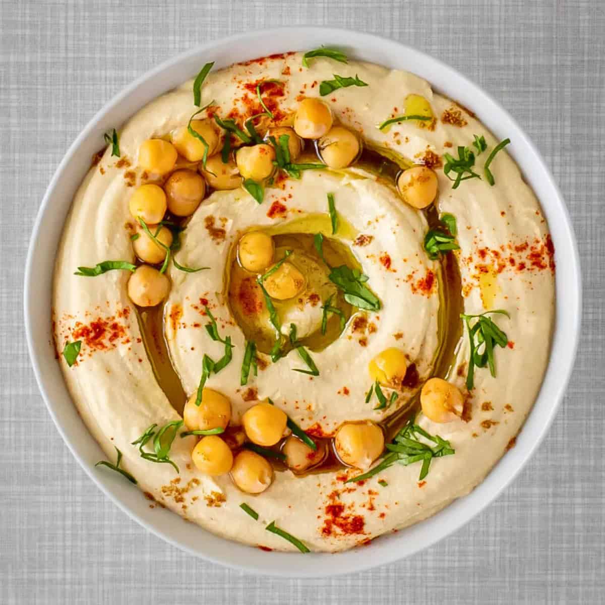 A bowl of hummus with chickpeas on top.