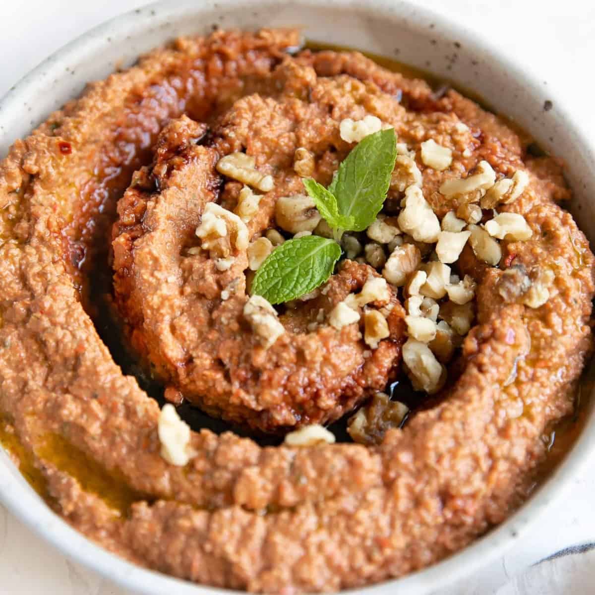 A dish of muhammara in a white bowl.
