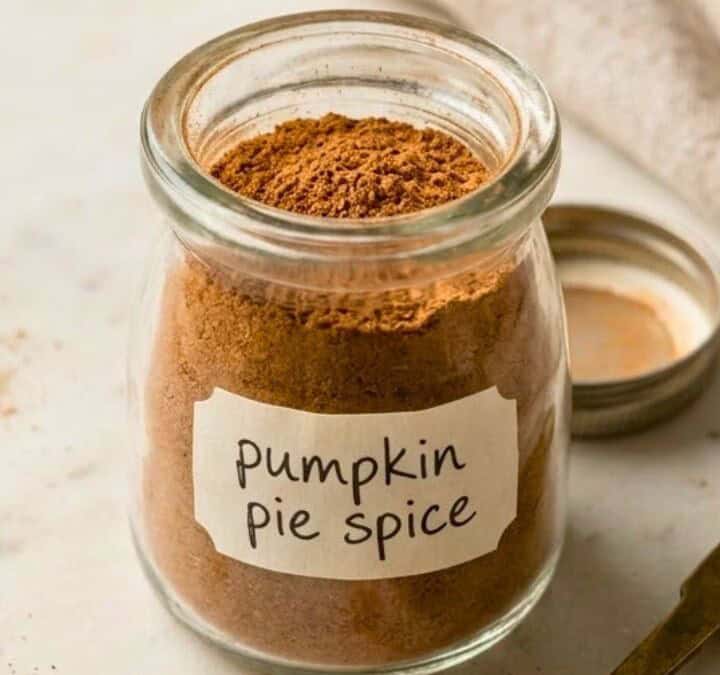 Glass jar filled with homemade pumpkin pie spice, featuring a handwritten label and a warm brown ground spice mixture.