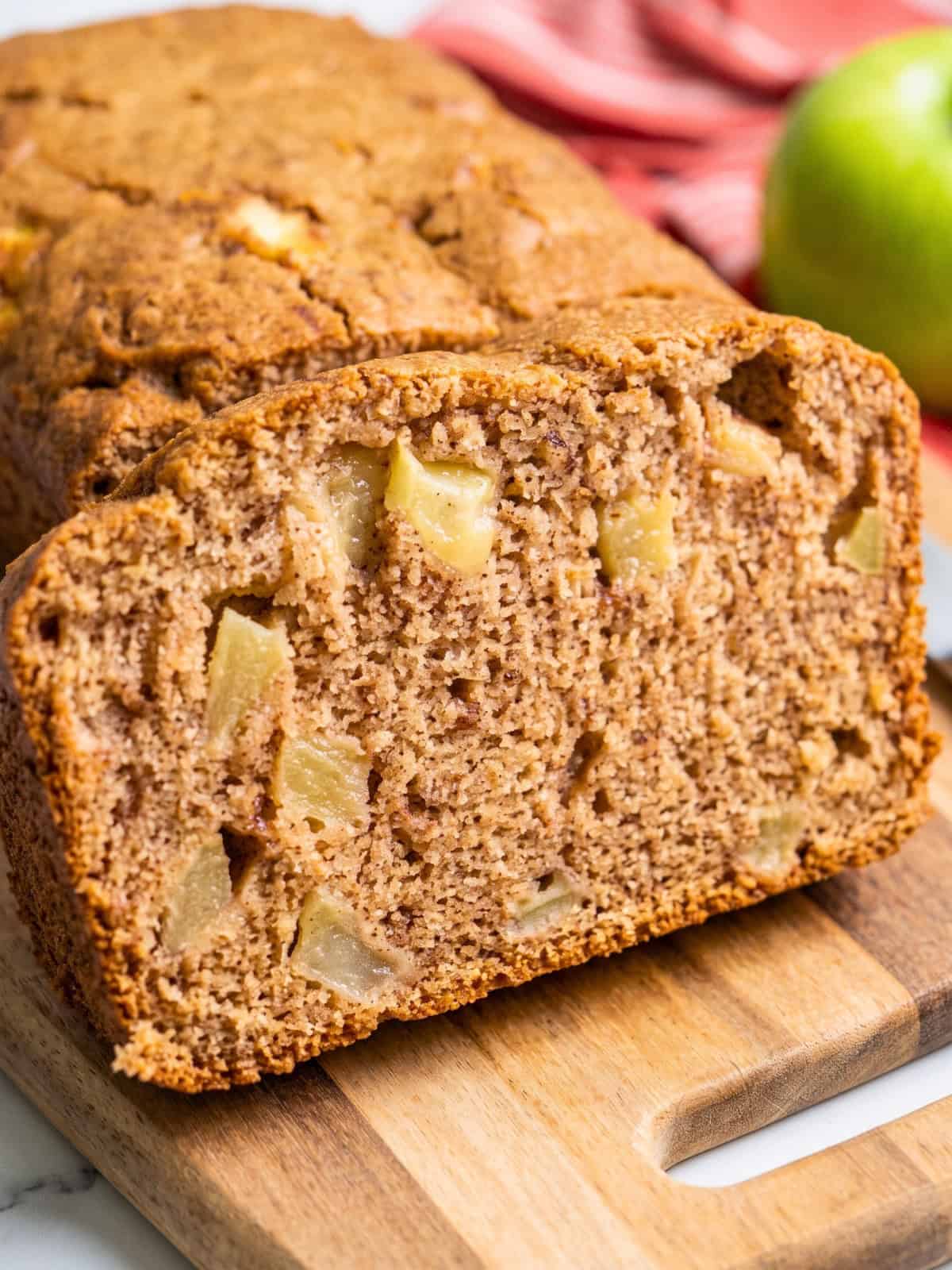 Close-up of moist vegan apple bread showing a tender cinnamon-spiced crumb with chunks of fresh apples.