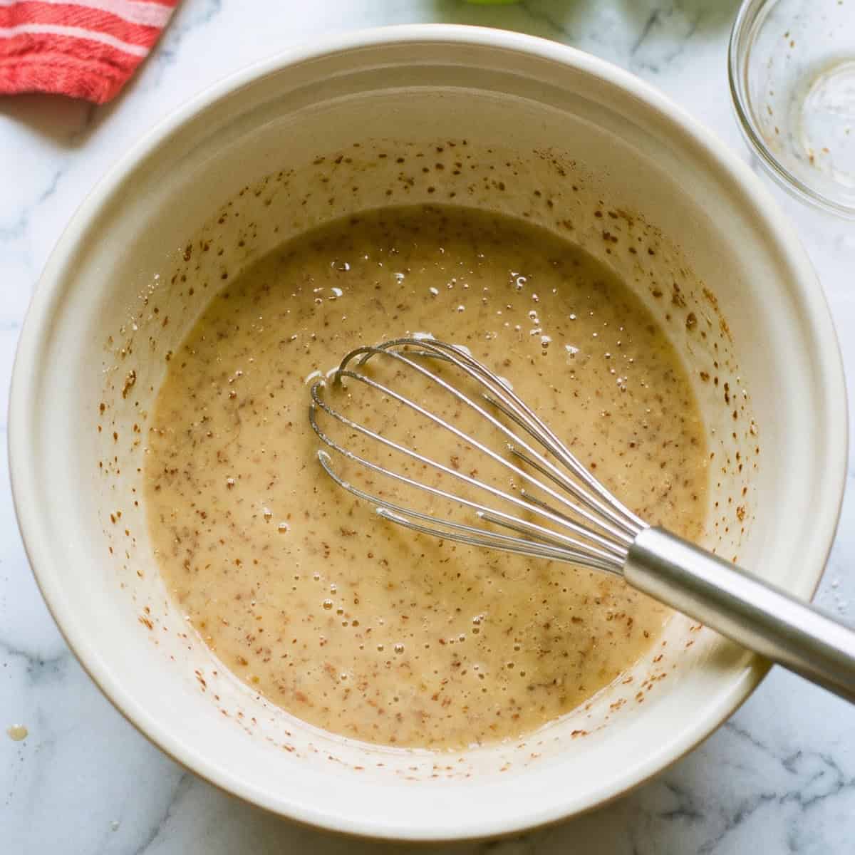 Wet ingredients for vegan apple bread combined in a mixing bowl with a whisk.
