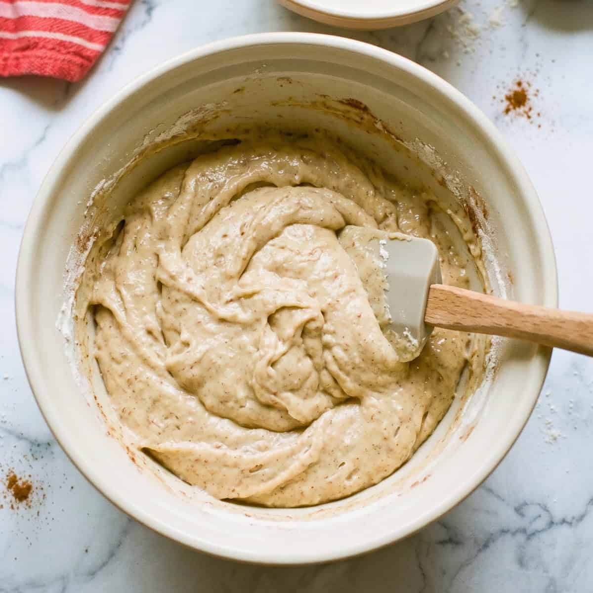 Thick vegan apple bread batter being mixed with a rubber spatula.