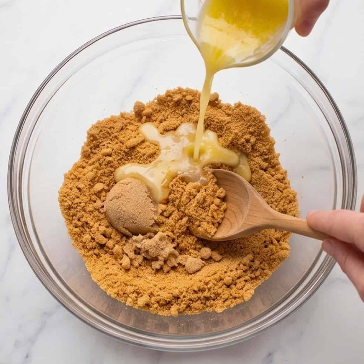 Melted vegan butter being poured into graham cracker crumbs to make a cheesecake crust.