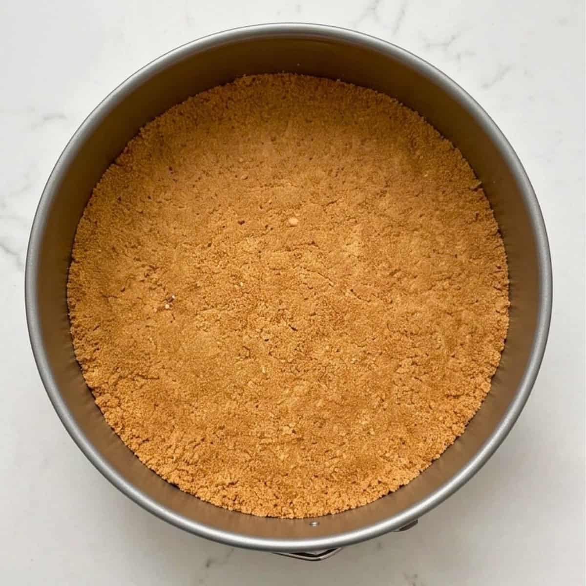Graham cracker crust evenly pressed into the bottom of a springform pan and set.