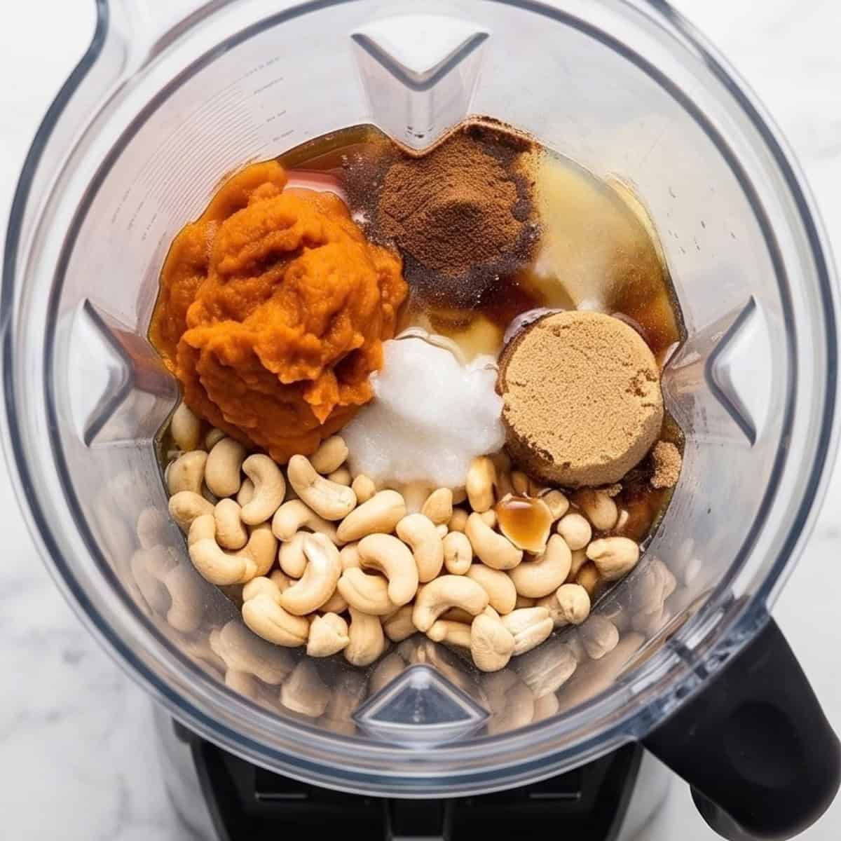 Cashews, pumpkin puree, brown sugar, spices, and other pumpkin cheesecake filling ingredients in a blender.