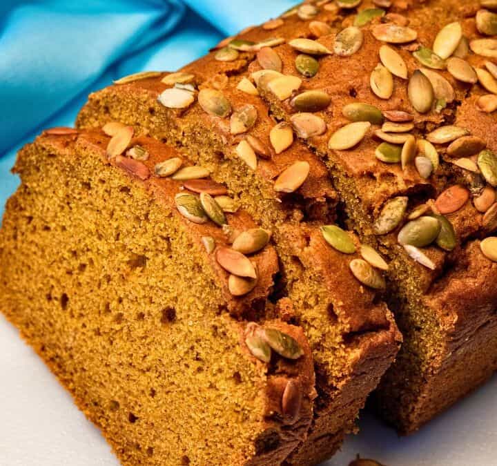 Close-up of sliced vegan pumpkin loaf topped with pumpkin seeds.