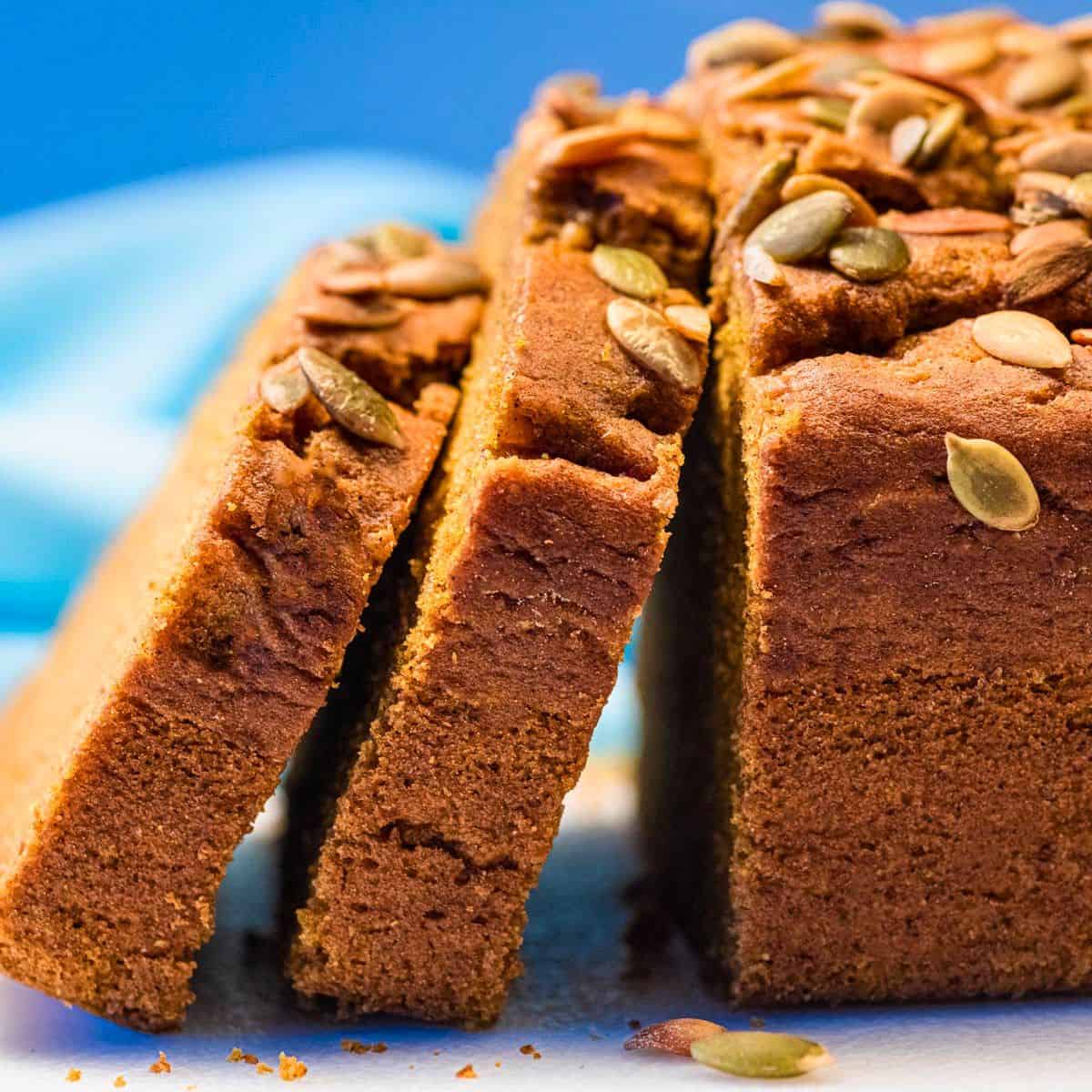 Thick slices of vegan pumpkin loaf leaning against the whole loaf.