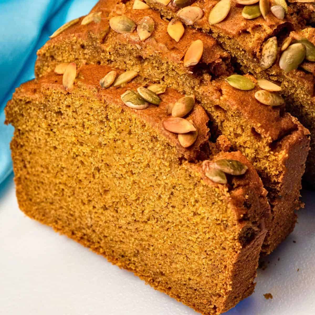 Moist slice of vegan pumpkin bread with pumpkin seeds on top.